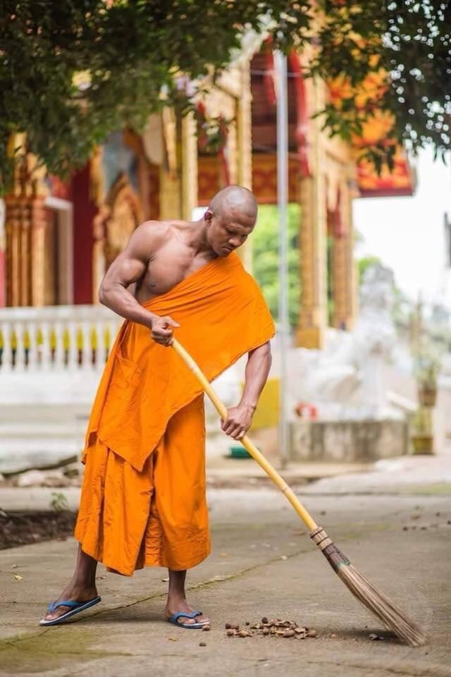 a man in an orange robe is holding a broom and looking down at the ground