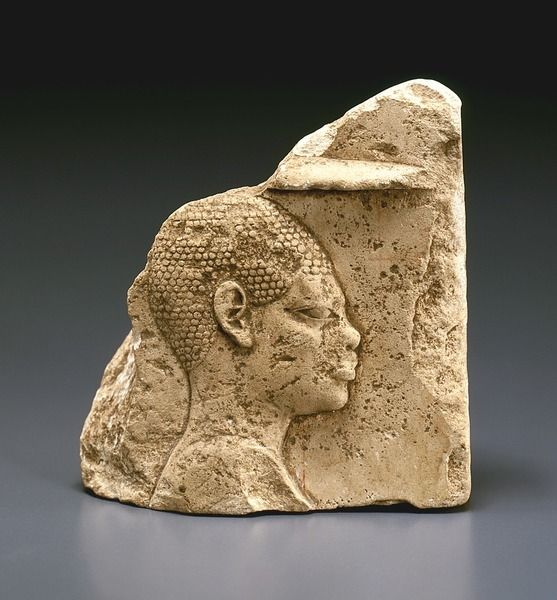 an ancient stone head with a crown on it