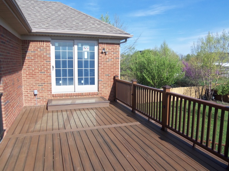 a wooden deck in front of a brick house