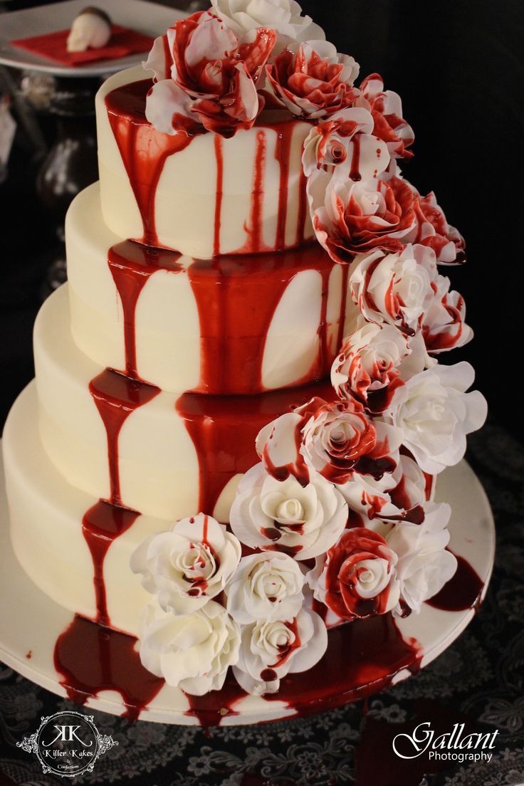 a three tiered cake with red and white icing on the top, decorated with flowers