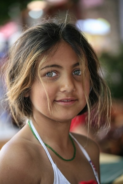 a close up of a young person wearing a tank top and smiling at the camera