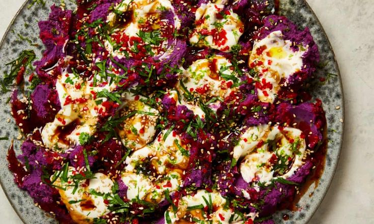 a plate filled with purple cabbage covered in feta cheese and garnished with herbs