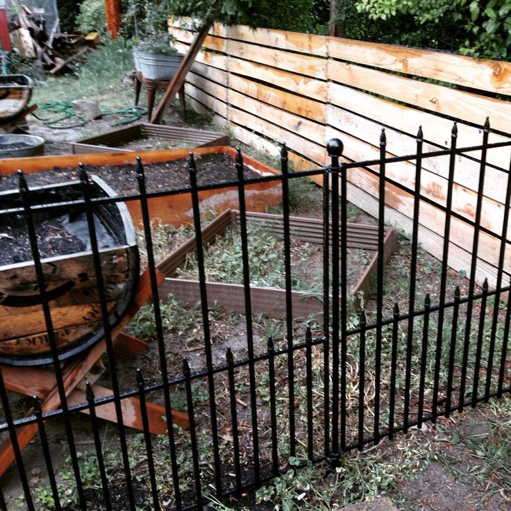 an old boat is sitting in the yard behind a fence