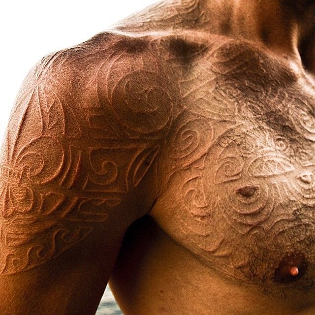 a man with no shirt on is looking at the camera while he has his arm and chest covered in intricate designs