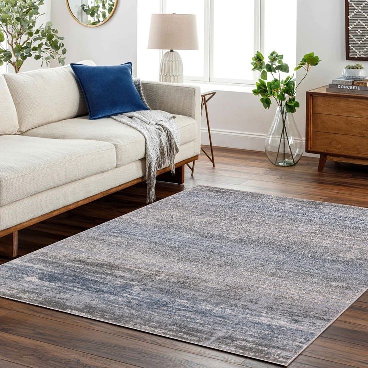 a living room with a couch, chair and rug on the floor in front of a window