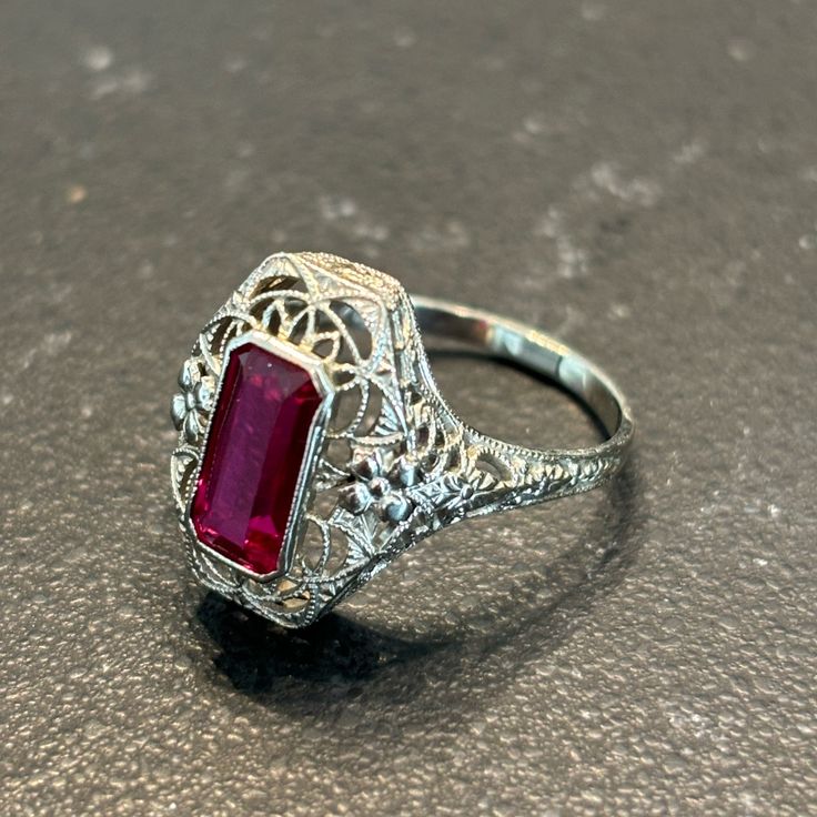 an antique style ring with a red stone in the center and filigrees