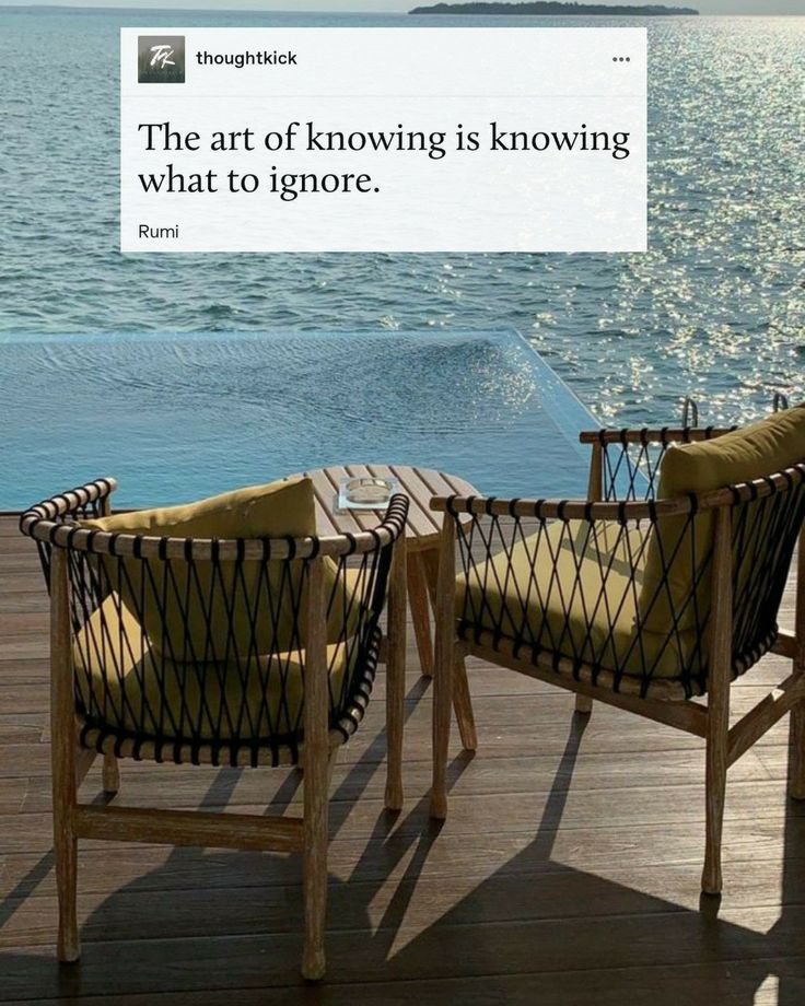 two chairs sitting on top of a wooden deck next to the ocean with a quote above them