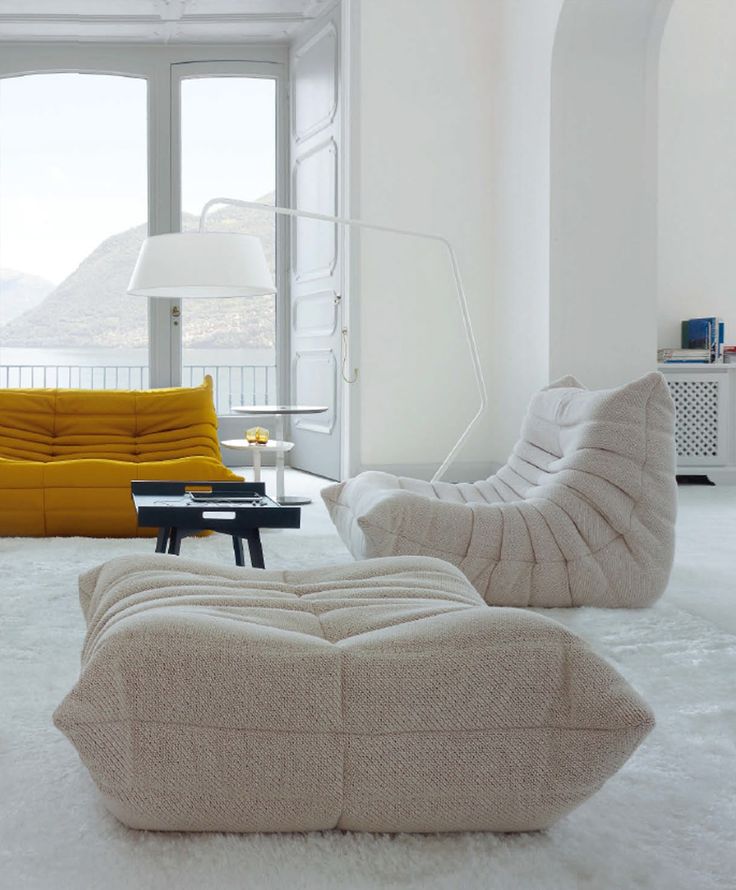 a living room filled with furniture next to a window covered in white fluffy rugs