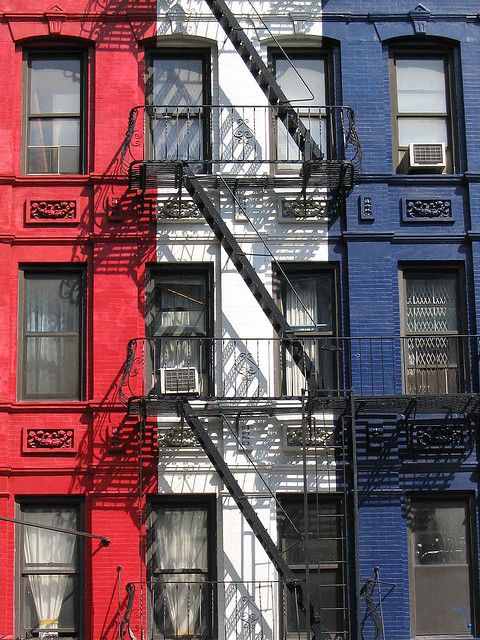 two red and one blue buildings with fire escapes