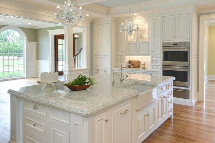 a large kitchen with white cabinets and marble counter tops