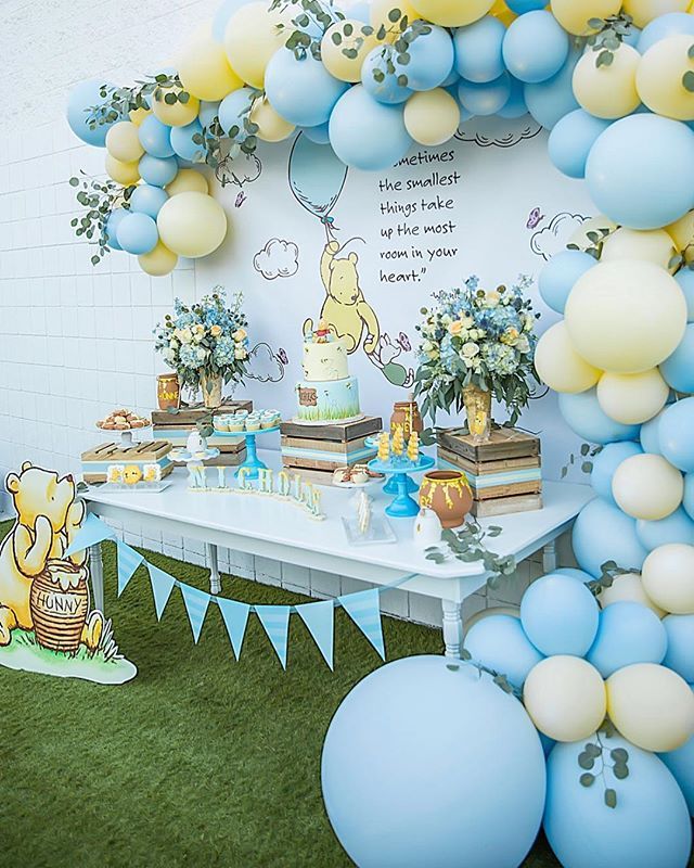 a winnie the pooh birthday party with balloons and desserts on a white table