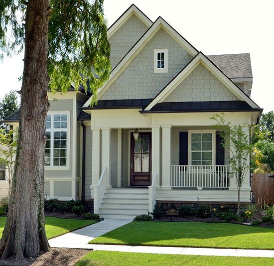 a white house with black trim on the front and side windows, grass in front