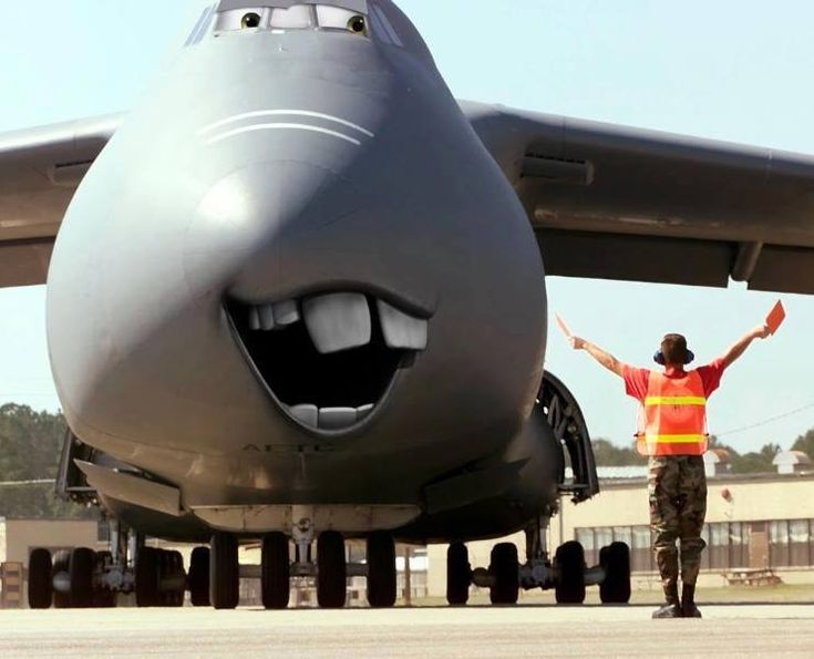 a man standing in front of an airplane with his arms up and eyes wide open