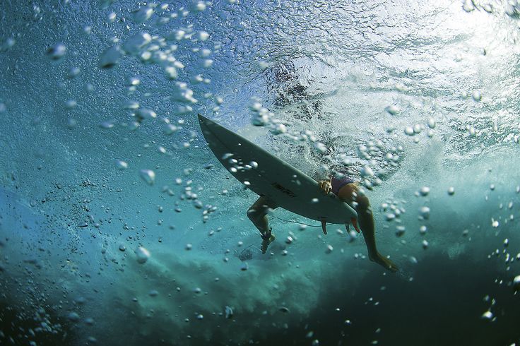 a man riding a surfboard under water in the ocean with bubbles on the surface