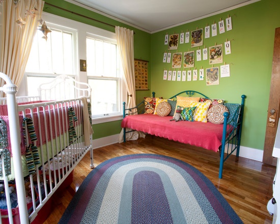 a baby's room with green walls and pictures on the wall, including a pink crib