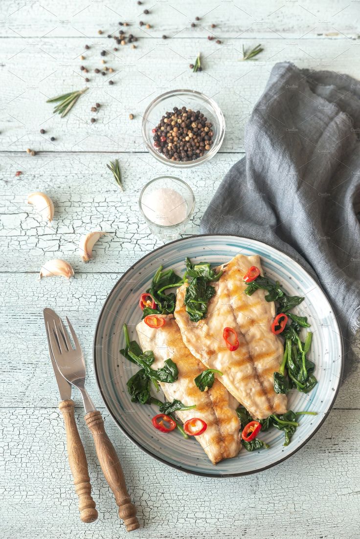 two fish fillets on a plate with spinach and spices