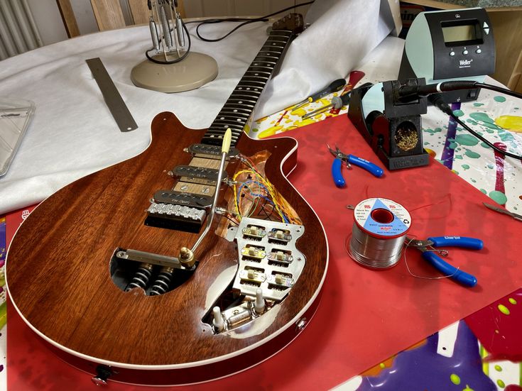 an electric guitar sitting on top of a table covered in wrapping paper and other items