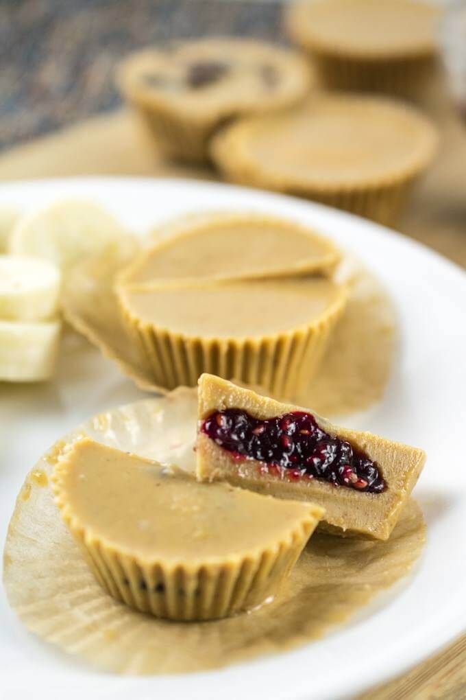 peanut butter and jelly cups on a white plate with banana slices in the back ground