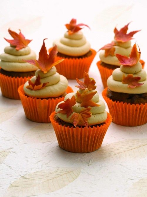 cupcakes decorated with leaves and frosting on a table