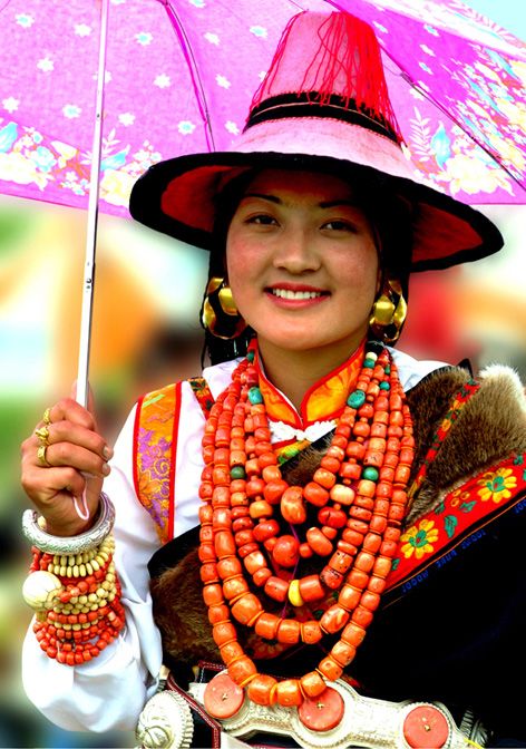 a woman with an umbrella and necklaces on her neck is smiling for the camera