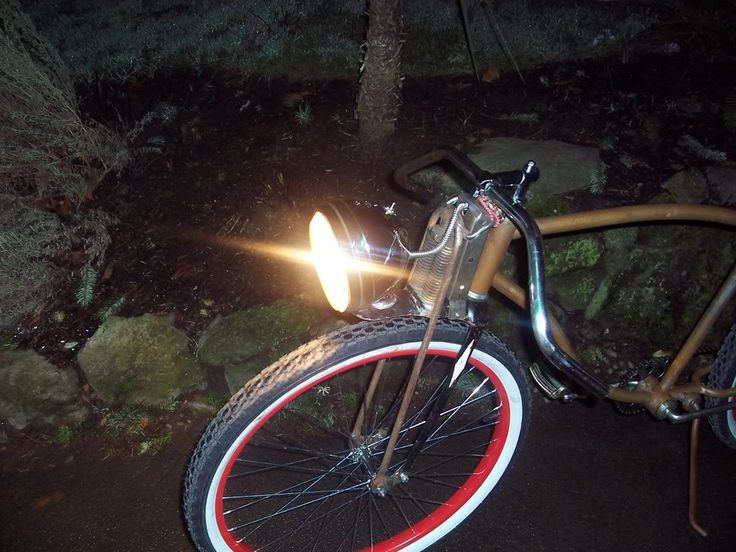 a bicycle with red and white rims is parked in the dark by some rocks