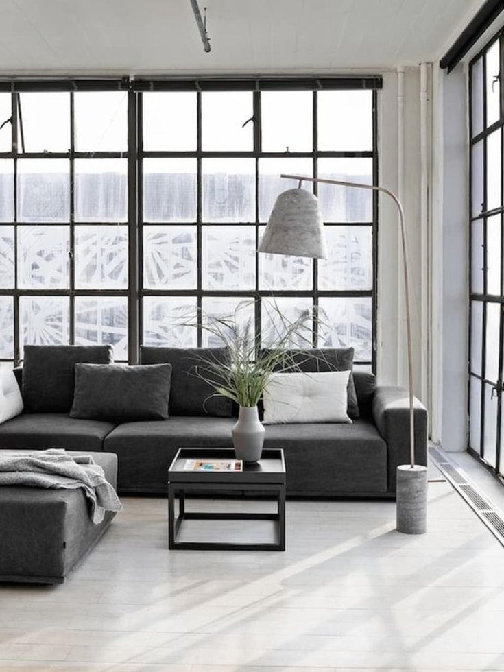 a living room filled with lots of furniture next to large windows and a floor lamp