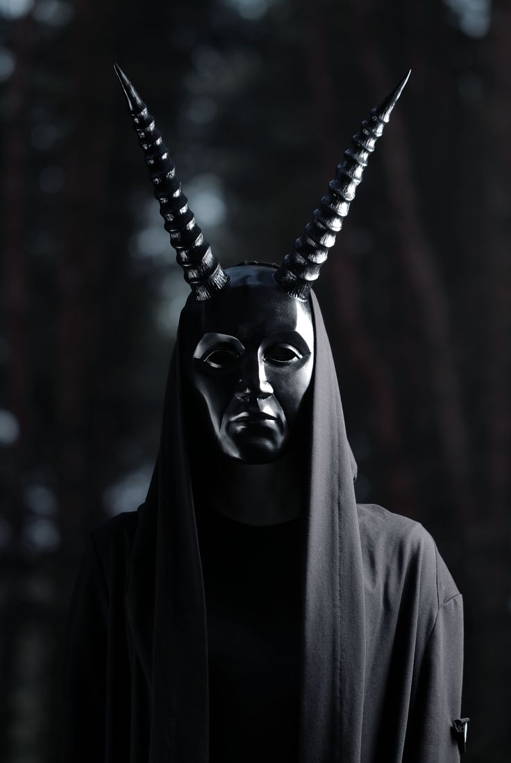 a person wearing a black mask with horns on their head and hood over their face