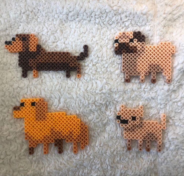 four perler bead dogs on a white blanket, each with different colors and sizes