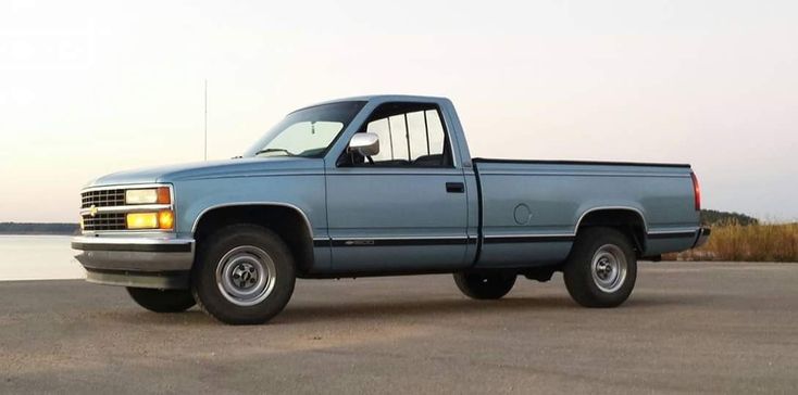 a blue pick up truck is parked by the water