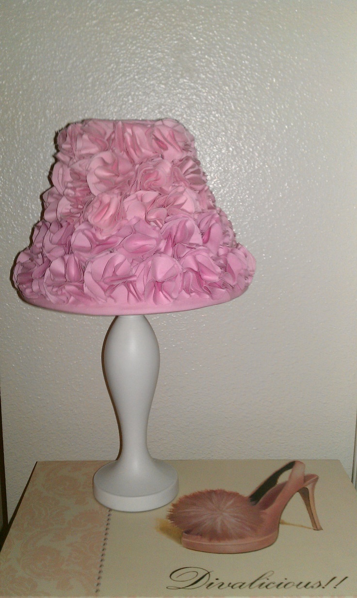 a pink lamp shade sitting on top of a table next to a shoe and magazine