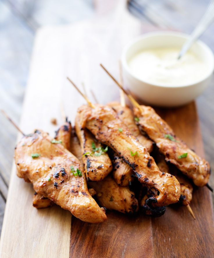 chicken skewers with toothpicks and ranch dressing on a wooden cutting board