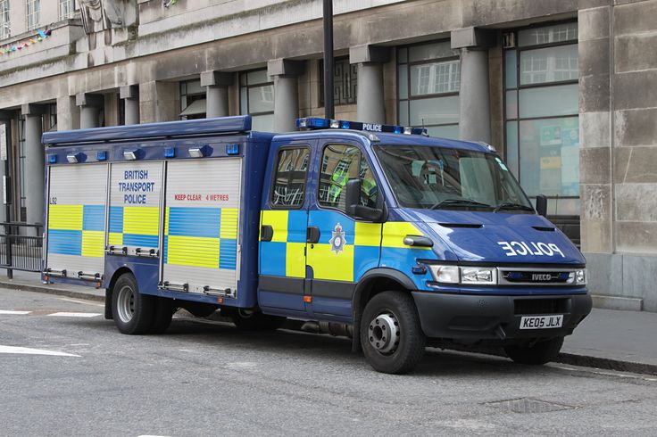 a blue and yellow police truck parked on the side of the road in front of a building