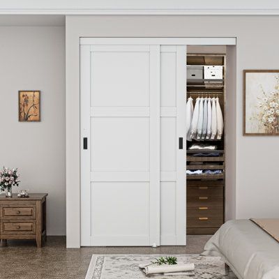 a bedroom with a bed, dresser and white closet doors that open to reveal clothes