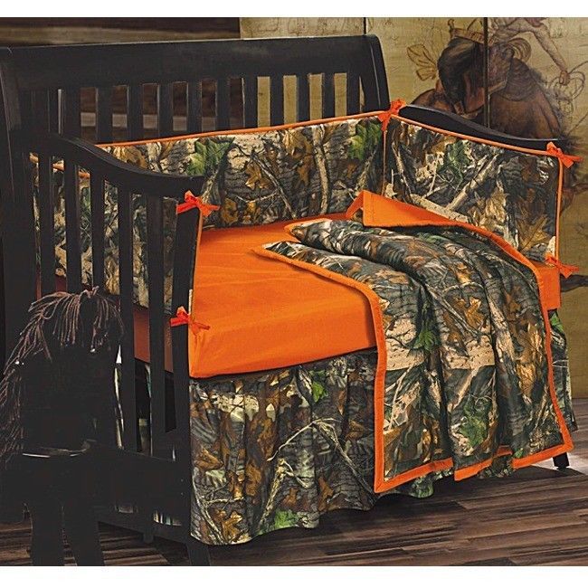 a baby crib with an orange blanket and camo bedding on the bottom