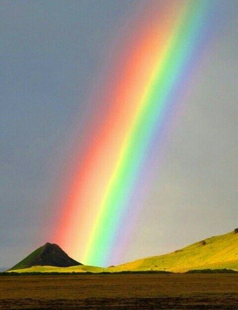 a rainbow in the sky over some hills