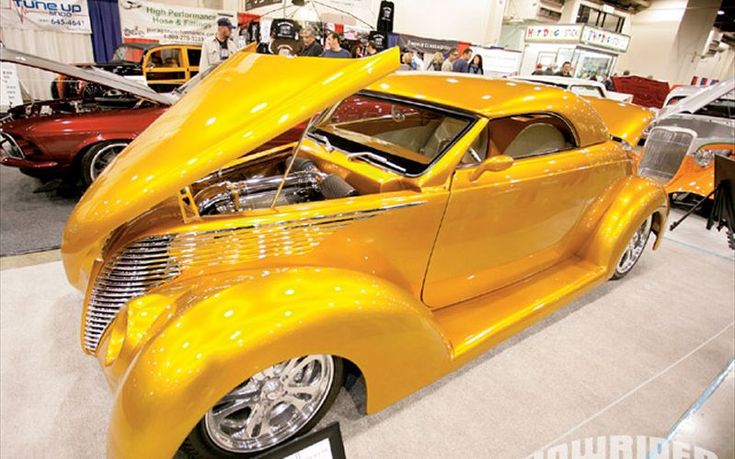 an old yellow car is on display in a museum