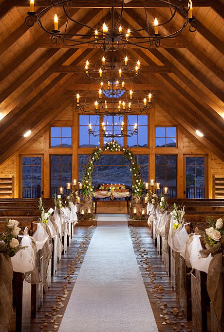 the aisle is decorated with white flowers and greenery as well as candles for an outdoor ceremony