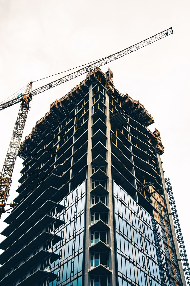 a tall building with lots of windows next to a crane