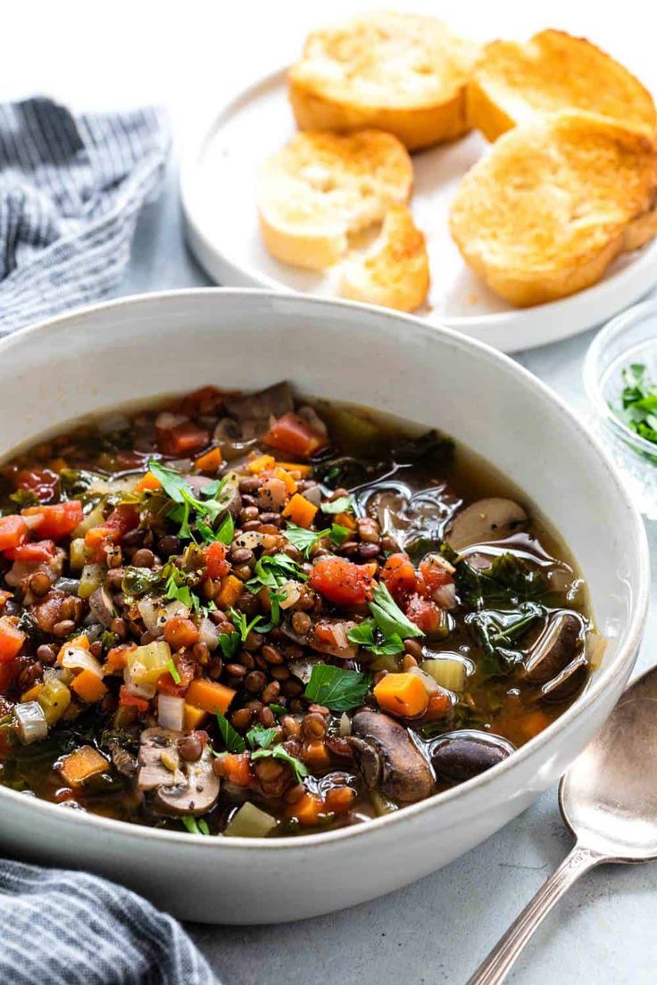 a white bowl filled with soup next to bread