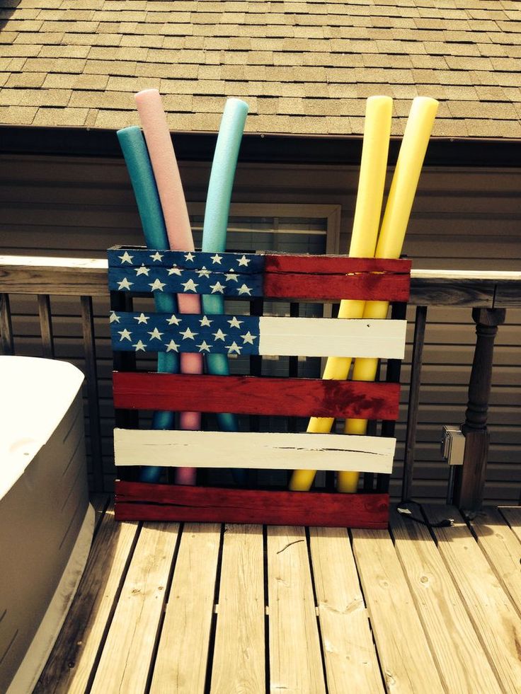 a wooden crate with candles and straws in it on a deck next to a bathtub