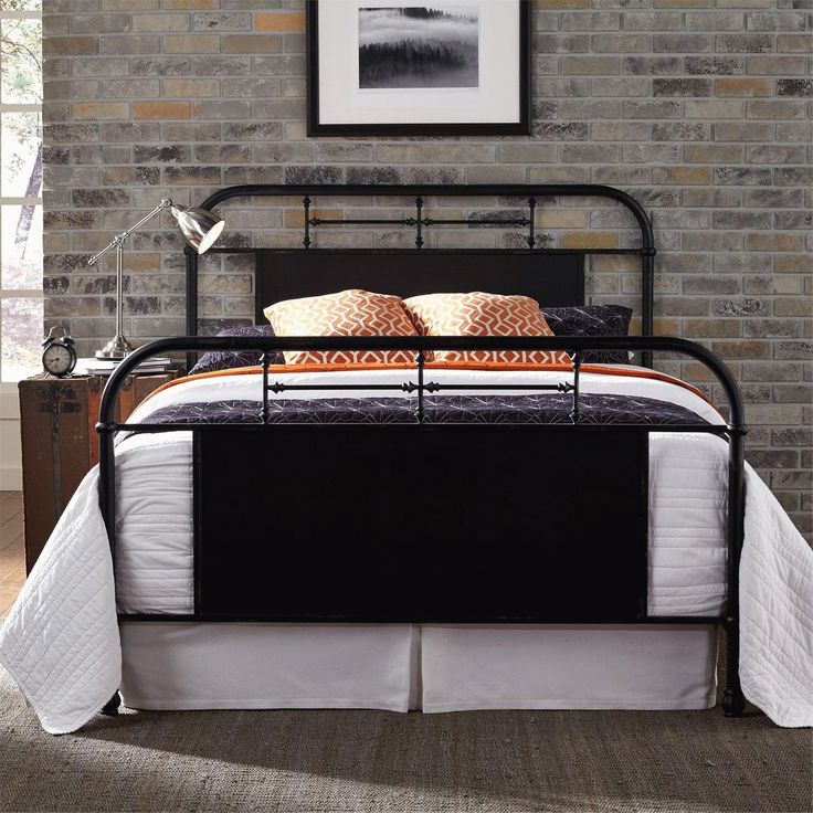 a bed with black metal frame and headboard in a room next to a brick wall