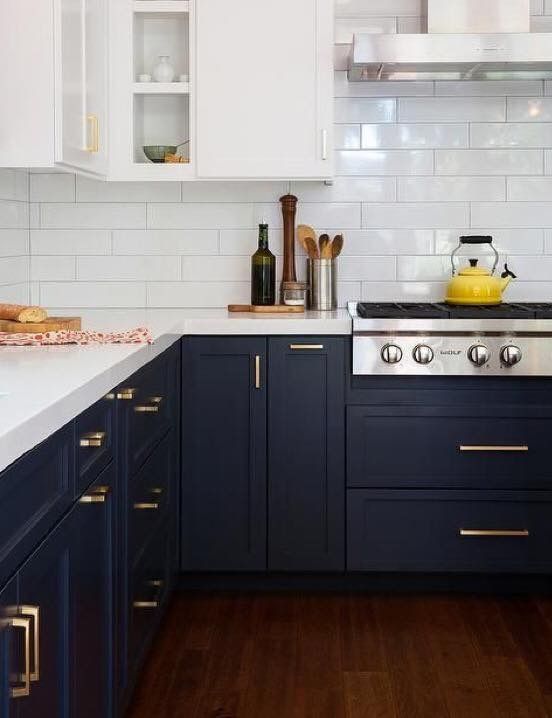 a kitchen with dark blue cabinets and white counter tops, gold pulls on the handles