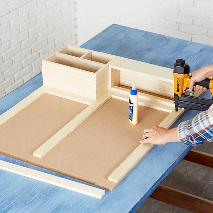 a person using a drill and glue to cut out the bottom part of a cabinet