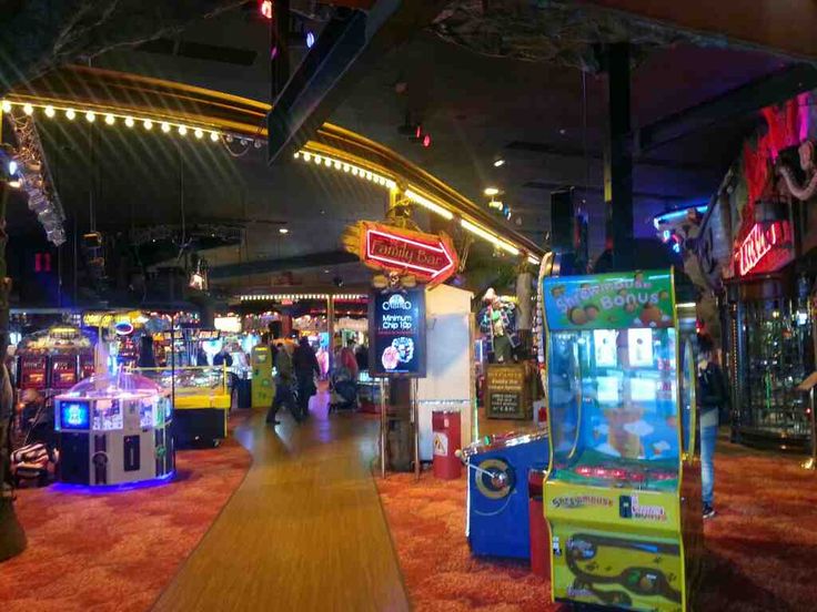 an indoor arcade with several games on the floor and people walking around in the background