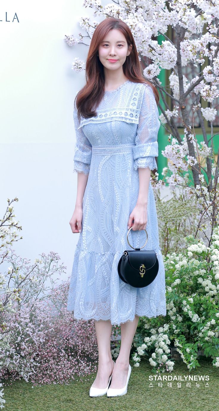 a woman in a blue dress holding a black purse