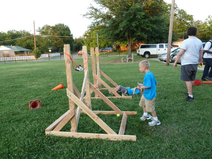 a young boy playing with a wooden structure in the grass