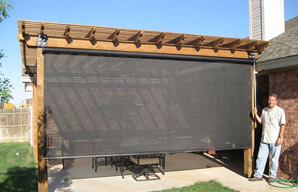 a man standing next to a large screen in the back yard on a sunny day