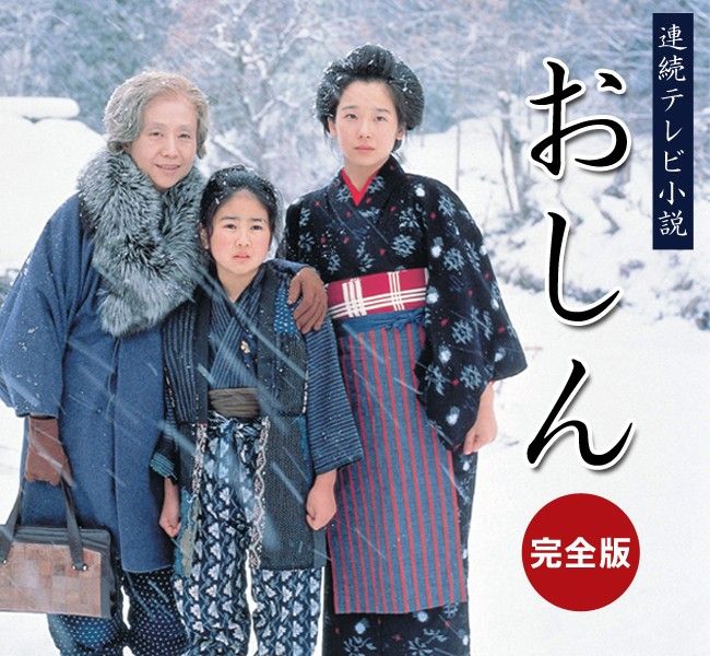 two women and one man are standing in the snow