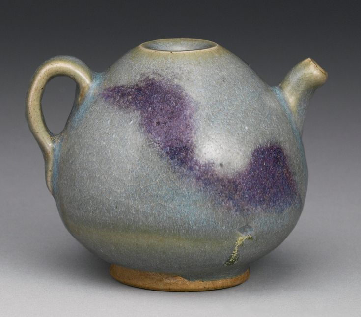 a ceramic teapot with purple speckles on the outside and inside, sitting on a gray surface