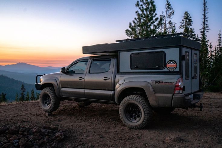 a truck with a camper attached to the back parked on top of a hill